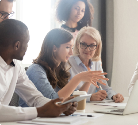 Coworkers explains concept in front of laptop surrounded by colleagues