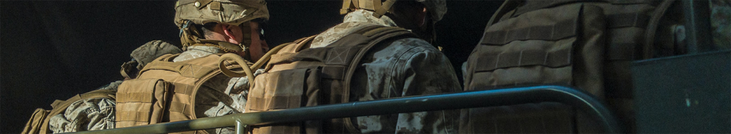 Soldiers facing away from the camera while sitting on a bench