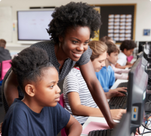 Teachers looks over student should at computer screen